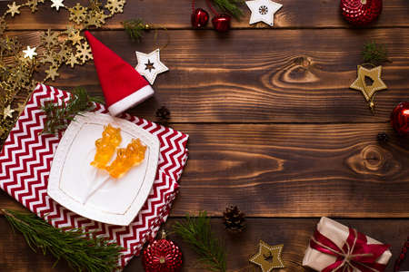 Two lollipops on stick in shape of symbol new year 2021 - bull on white saucer, towel with ornaments and Christmas decor on wooden background. Jewelry stars, beads, ball, fir. Flat lay, copy spaceの写真素材
