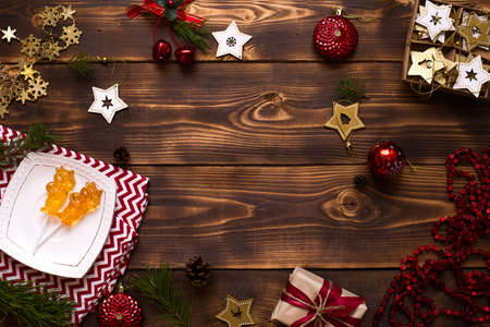 Two lollipops on stick in shape of symbol new year 2021 - bull on white saucer, towel with ornaments and Christmas decor on wooden background. Jewelry stars, beads, ball, fir. Flat lay, copy spaceの写真素材