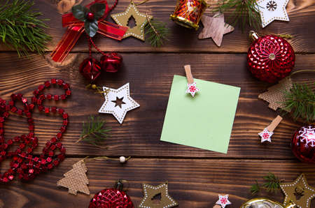 Christmas flat lay of red balloons and wooden stars and clothespins on a dark background with a square sheet for notes in the center. New year's frame, space for text. Xmas toys, beads, pine branchesの写真素材
