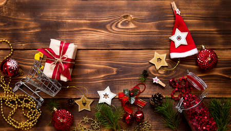 Christmas flat lay on the theme of shopping, buying gifts for the new year. Black Friday, sale, decor of stars, spruce branches, ball, beads, garlands, cones on a wooden background. Space for textの写真素材