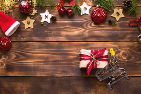 Christmas flat lay on the theme of shopping, buying gifts for the new year. Black Friday, sale, decor of stars, spruce branches, ball, beads, garlands, cones on a wooden background. Space for textの写真素材