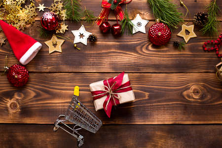 Christmas flat lay on the theme of shopping, buying gifts for the new year. Black Friday, sale, decor of stars, spruce branches, ball, beads, garlands, cones on a wooden background. Space for textの写真素材