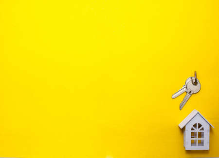 White wooden house symbol and keys on a yellow background. Cottage construction concept, layout and design, architectural plan, moving to a new house, realtor Agency. Space for text, flatlyの写真素材