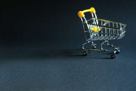 Empty grocery cart in the defocus from a supermarket on a black background. Black Friday, shopping cart, shopping, online store, sale, discounts. Space for text. Blurredの写真素材