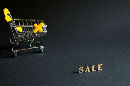 Shopping cart and the inscription "Sale" on a black background. Black Friday, discounts, sale, shopping, interest sign. Space for textの写真素材