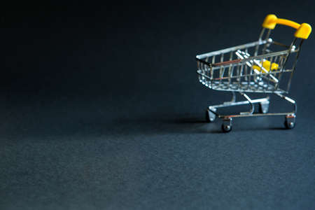 Empty grocery cart in the defocus from a supermarket on a black background. Black Friday, shopping cart, shopping, online store, sale, discounts. Space for text. Blurredの写真素材