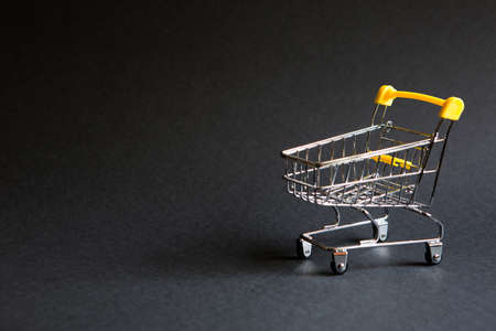 Empty grocery cart from a supermarket on a black background. Black Friday, shopping cart, shopping, online store, sale, discounts. Space for textの写真素材