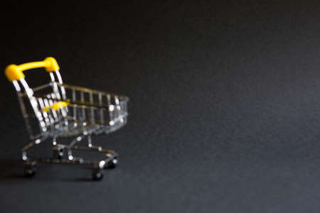 Empty grocery cart in the defocus from a supermarket on a black background. Black Friday, shopping cart, shopping, online store, sale, discounts. Space for text. Blurredの写真素材