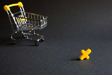 Yellow plastic sign percent on a black background with the shopping cart. Black Friday, discount percentage, shopping, buying and selling, promotion. Space for textの写真素材