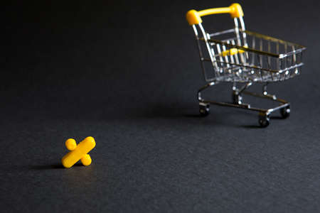 Yellow plastic sign percent on a black background with the shopping cart. Black Friday, discount percentage, shopping, buying and selling, promotion. Space for textの写真素材