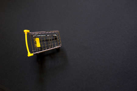 Empty grocery cart from a supermarket on a black background. Black Friday, shopping cart, shopping, online store, sale, discounts. Space for textの写真素材
