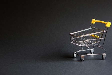 Empty grocery cart from a supermarket on a black background. Black Friday, shopping cart, shopping, online store, sale, discounts. Space for textの写真素材