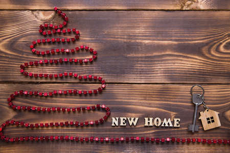 Christmas tree on wooden background with key to the house and keychain with inscription in English "new home". Building or buying a house in New year. Mortgage, real estate rental. copy space, flatlyの写真素材