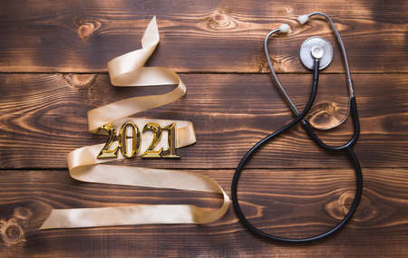 Christmas flat lay on a medical theme. Decorations for the new year from stars, ball, ribbons, Santa hats, and a doctor's stethoscope. Wooden background, space for textの写真素材