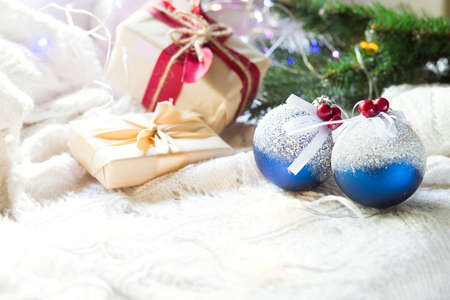 Blue balls with artificial snow, Christmas gift boxes and decorations on a white knitted blanket. New year, festive atmosphere, spruce branch, comfort. Space for textの写真素材