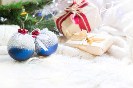 Blue balls with artificial snow, Christmas gift boxes and decorations on a white knitted blanket. New year, festive atmosphere, spruce branch, comfort. Space for textの写真素材