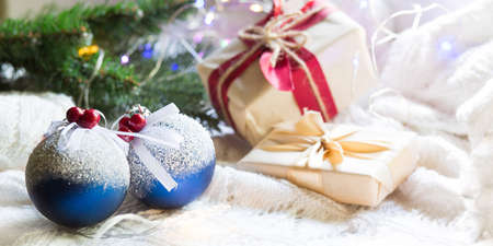 Blue balls with artificial snow, Christmas gift boxes and decorations on a white knitted blanket. New year, festive atmosphere, spruce branch, comfort. Space for textの写真素材