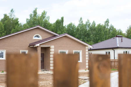 Wooden fence on the background of the cottage. View from the window of a house in the village. Moving to the countryside, building, mortgage, rent and purchase real estate. Cottagecore. Copy spaceの写真素材