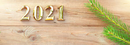 Gold numbers 2021 on a wooden background with Christmas decorations: green branches of spruce, red ball. New Year concept, frame, top view. Copy space. Merry Christmas and Happy New Year symbol'sの写真素材