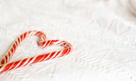 Christmas candy cane striped Santa in the form of heart on a white knitted blanket. A symbol of love, a gift to a loved one, a sweet treat. New Year. Space for textの写真素材