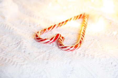 Christmas candy cane striped Santa in the form of heart on a white knitted blanket. A symbol of love, a gift to a loved one, a sweet treat. New Year. Space for textの写真素材