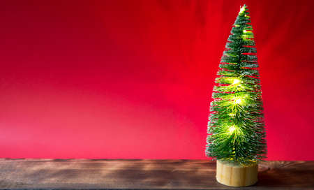 Christmas tree on a red background with lights of garlands, caramel striped cane, Santa hat, tinsel. New year, festive atmosphere. Copy spaceの写真素材