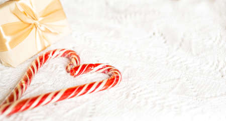 Christmas candy cane striped Santa in the form of heart on a white knitted blanket. A symbol of love, a gift to a loved one, a sweet treat. New Year. Space for textの写真素材