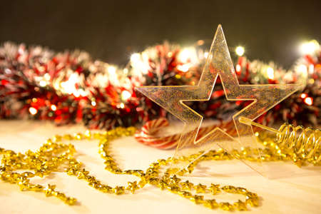 Christmas decorations with garland lights in a blur. Transparent gold star, beads, candy canes, red tinsel. New year. Backgroundの写真素材