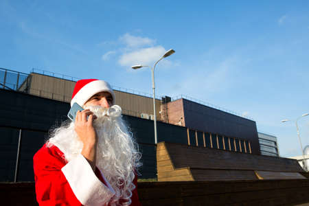 Modern Santa Claus talking on the phone. Ordering the services of an animator for the Christmas and new year. Online greetings via the Internet and mobile communication, social distanceの写真素材