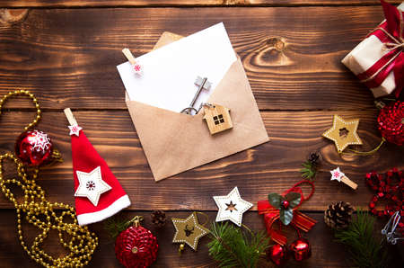 Christmas flat lay on a wooden background with keys to new house in the center with a envelope with a note sheet. New year, transfer, shares of the mortgage, the rental of a cottage. Space for textの写真素材