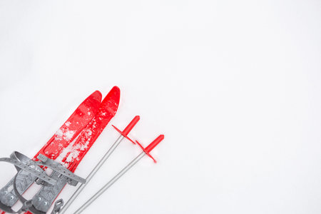 Children's red skis with sticks -layout in the snow. Children's winter sport, outdoor activities,...