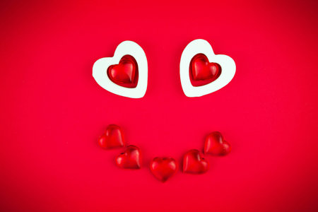 Cute face made of hearts on a red background-a smile for Valentine's day. Funny Express the feelings...
