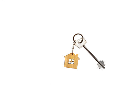 Key chain in the shape of wooden house with key on a white background, isolate. Building, design,...