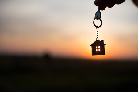 Silhouette of a house figure with a key, a pen with a keychain on the background of the sunset. They dream of a house, building, moving to a new house, mortgages, renting and buying real estate. Copy spaceの素材 [FY310162776650]