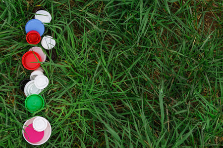 Colorful plastic bottle caps on the green grass. Volunteer charity event "Good lids" to help orphaned children. Eco-friendly garbage collection, plastic recyclingの写真素材