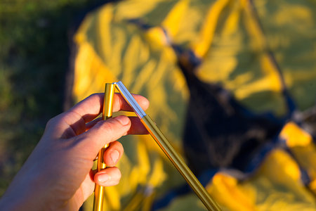 Aluminum mounting arcs for the installation of a tourist yellow tent in the hand close-up. Lightweight equipment for tourism. Outdoor activities, assembly instructions, domestic ecotourism. Copy spaceの写真素材