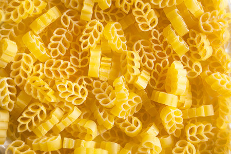 Dry pasta in the form of a wheat ear close-up. Culinary background, texture, pattern of yellow macaroni. Copy space. Grain product made from flourの写真素材