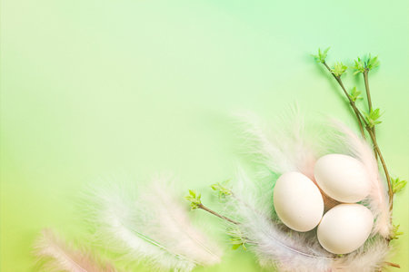 White Easter eggs in a delicate nest of colored feathers with unfurled leaf buds on the branches....