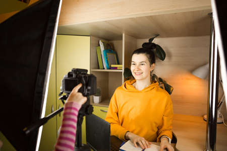 A woman leads a live vlog broadcast, records a video on a camera from home. Remote communication, new reality, blogging, video conferencingの写真素材