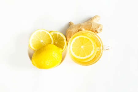 Medicinal tea in a cup, ginger, lemon-strengthen the immune system in the cold season. Vitamin drink for health and ingredients on a white background.の写真素材