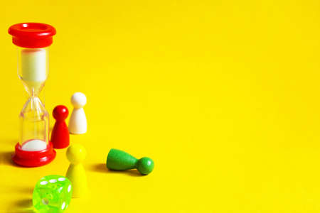Layout of board games on a yellow background: dice, chips, hourglass timer. Entertainment at home for children and adults. Copy spaceの写真素材