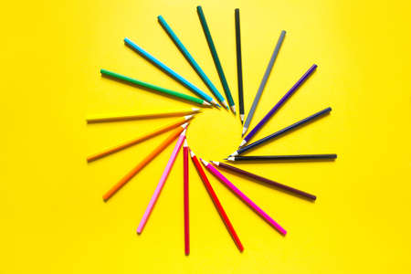 Set of colorful pencils on a yellow background is laid out in a circle in the shape of the sun. Copyspace, frame. Back to school, artist, drawing lessons. Stationery for creativity, drawの写真素材