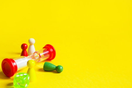 Layout of board games on a yellow background: dice, chips, hourglass timer. Entertainment at home...
