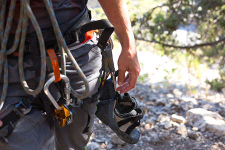 Climbing equipment on a male climber: rock shoes, rope, quickdraw, safety device, harness. Sports mountain tourism, active lifestyle, extreme sportsの写真素材
