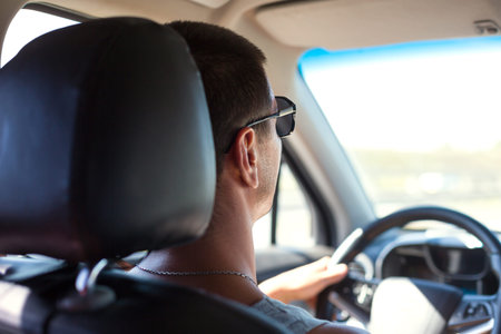A man with dark glasses is driving a car. Road safety, traffic rules, auto travel, navigator