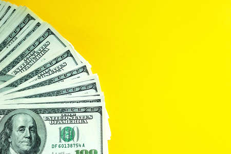 A stack of $ 100 bills on a yellow background. Concept Business, finance, investment, cash payment, savings, and wealth. Copy spaceの写真素材