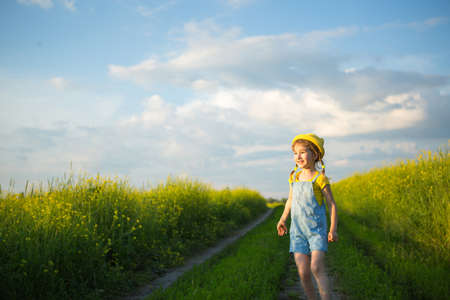 Cheerful girl in a yellow hat in a summer field laughs and smiles. Joy, sunny weather, holidays. A remedy for mosquitoes and insects. Lifestyle, kind face, close-up portrait, enjoying freedomの写真素材