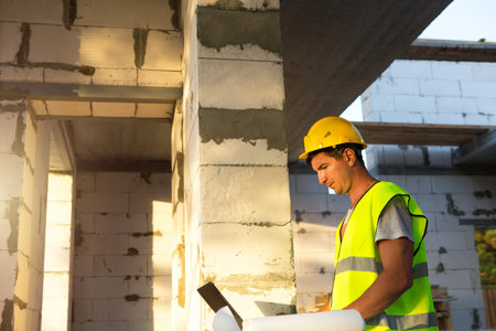 Construction engineer on the construction site of a house made of porous concrete blocks works at a...