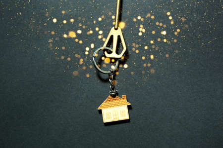 The key to the house with gold sequins and glow on a black background. Building, design, project, moving to new home, mortgage, booking, rent and purchase real estate. New Year, Christmasの写真素材
