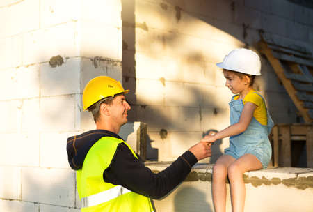 Dad and daughter are at construction site of their future home. The choice of the future profession of a builder is inherited by child. The expectation of moving, the dream of a house. Mortgage, loanの写真素材